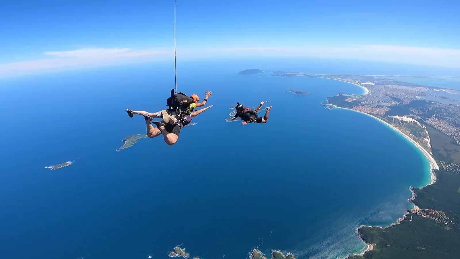 Zwei Tandemsprünge mit geöffneten Fallschirmen über der Praia de Tucuns